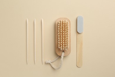 Photo of Set of pedicure tools and flowers on beige background, flat lay