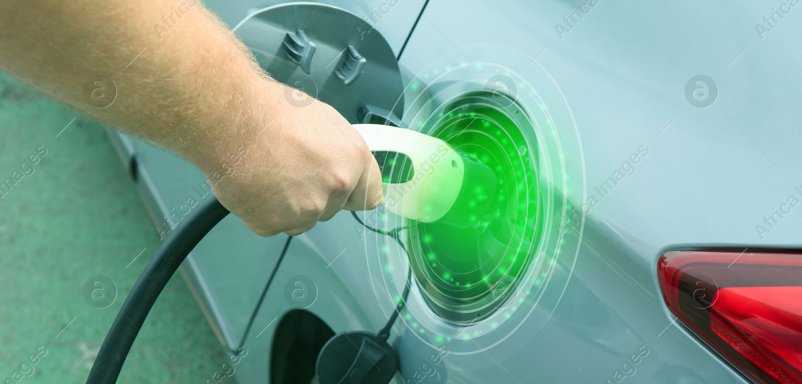 Image of Man inserting plug into electric car socket at charging station outdoors, closeup. Banner design. Round pulse waves representing energy