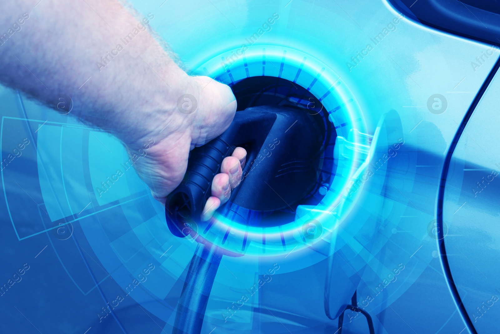 Image of Man inserting plug into electric car socket at charging station outdoors, closeup