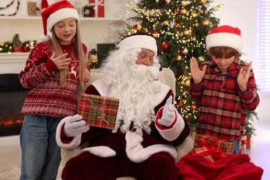 Christmas celebration. Santa Claus giving gift box to emotional kids at home