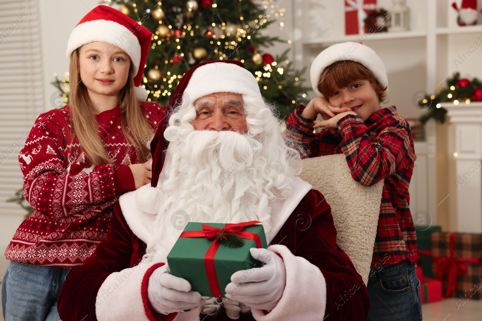 Photo of Christmas celebration. Santa Claus with kids and gift box at home