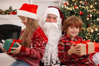 Christmas celebration. Santa Claus and kids with gift boxes at home