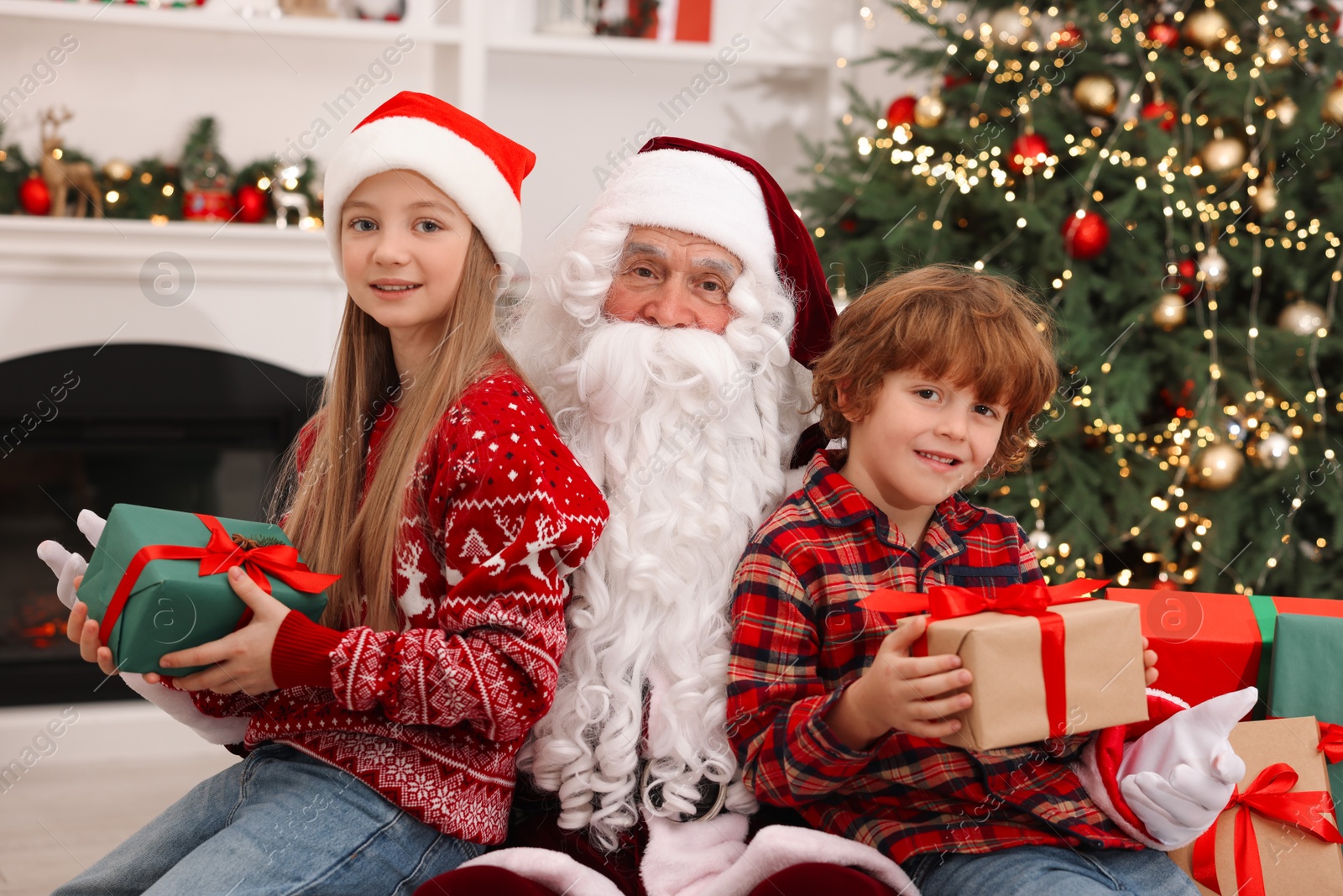 Photo of Christmas celebration. Santa Claus and kids with gift boxes at home