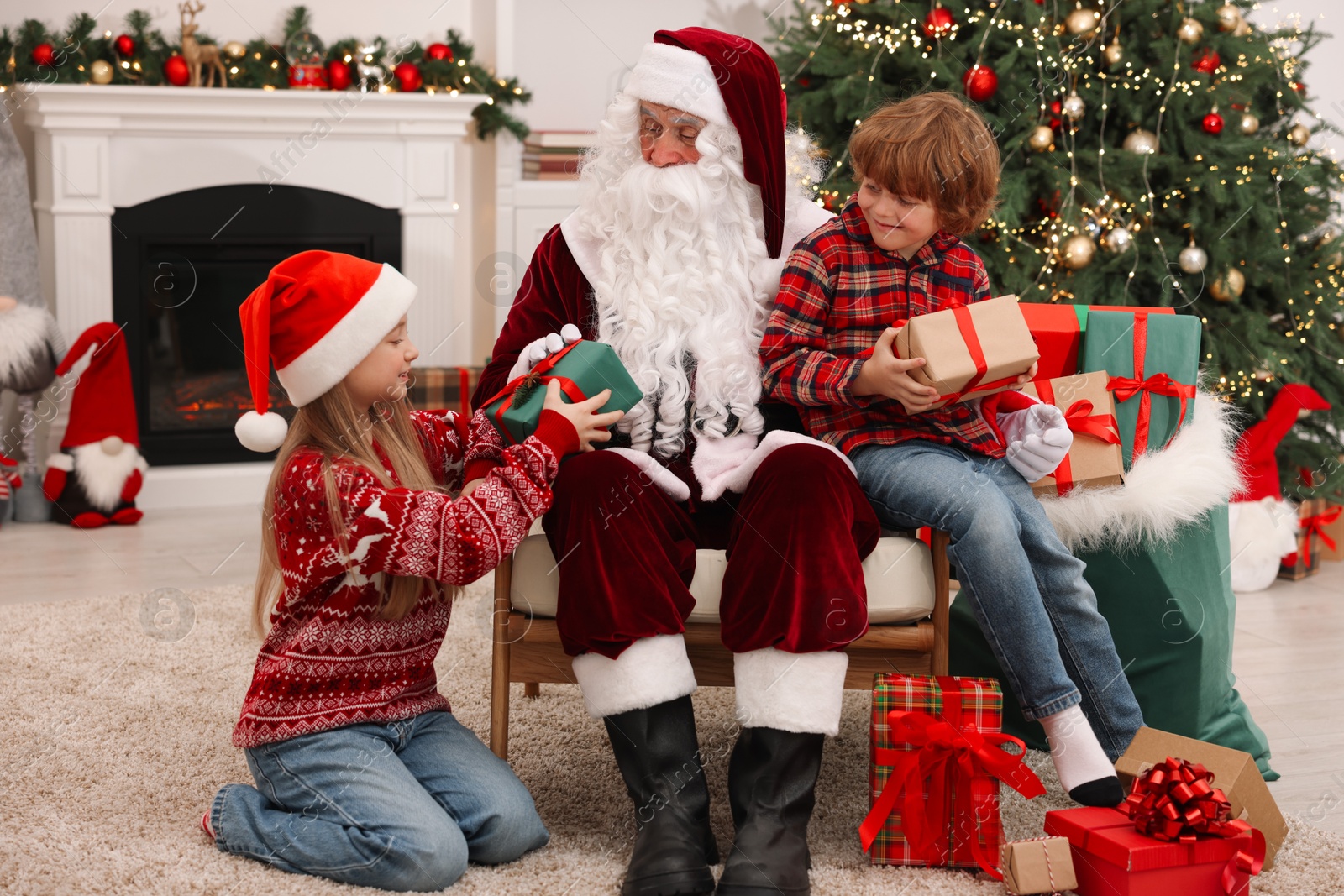 Photo of Christmas celebration. Santa Claus and kids with gift boxes at home