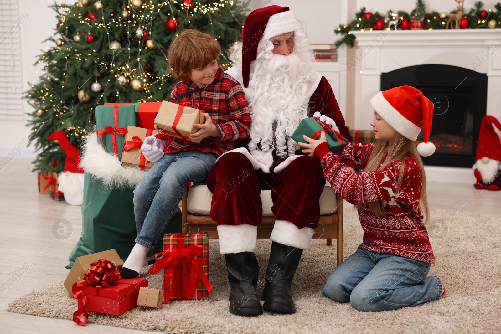 Photo of Christmas celebration. Santa Claus and kids with gift boxes at home