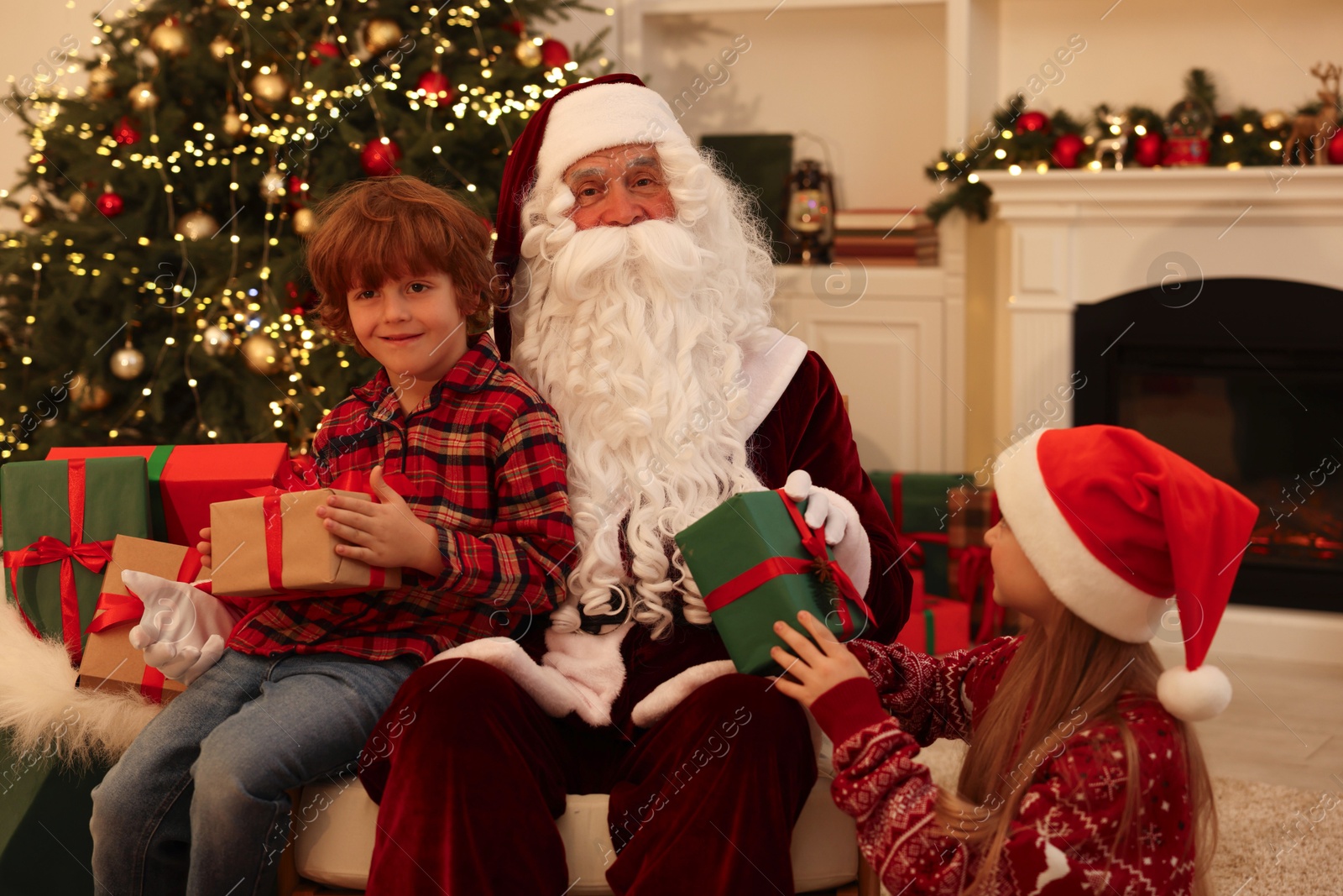 Photo of Christmas celebration. Santa Claus and kids with gift boxes at home