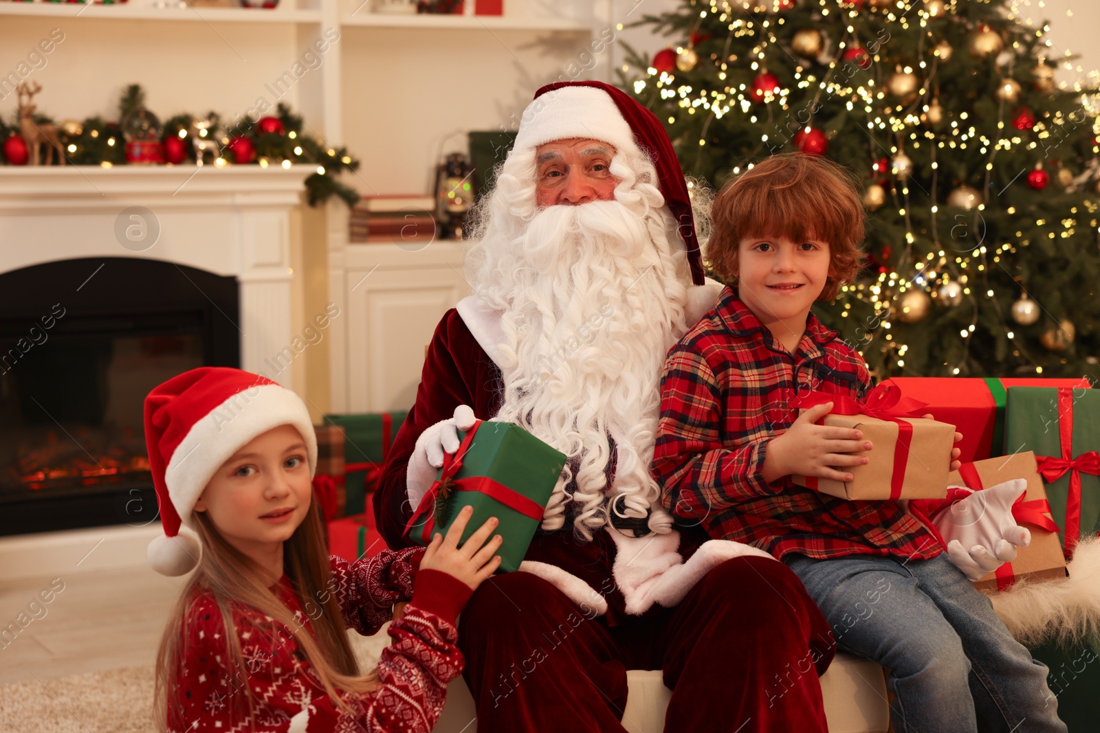 Photo of Christmas celebration. Santa Claus and kids with gift boxes at home