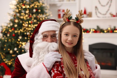 Photo of Christmas celebration. Santa Claus and girl at home