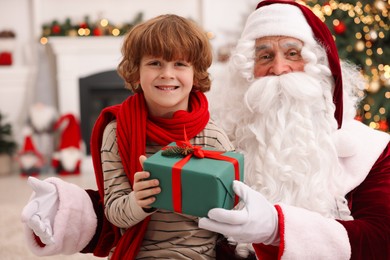 Photo of Christmas celebration. Santa Claus and boy with gift box at home