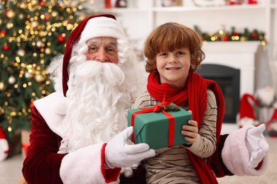 Christmas celebration. Santa Claus and boy with gift box at home