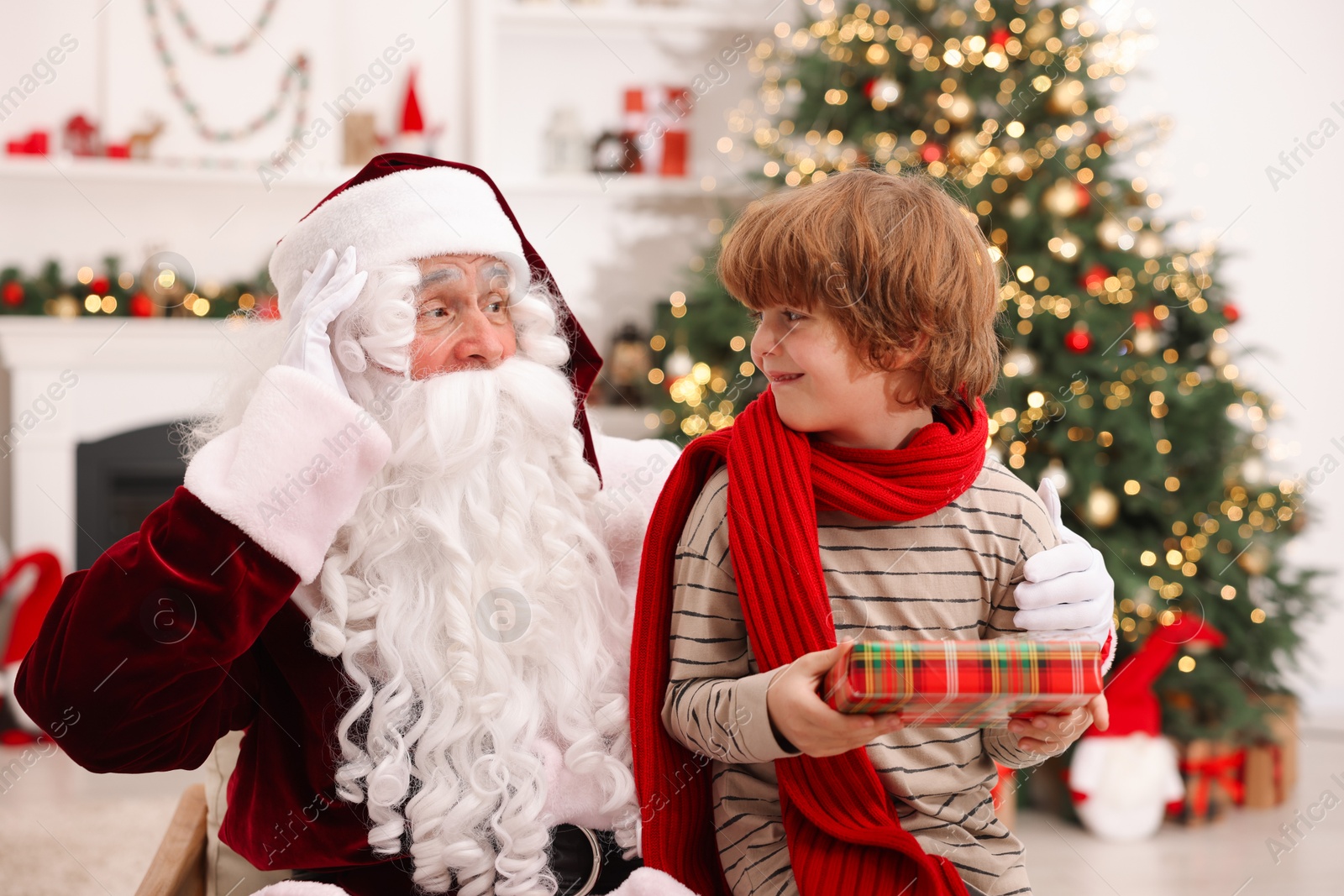 Photo of Christmas celebration. Santa Claus and boy with gift box at home