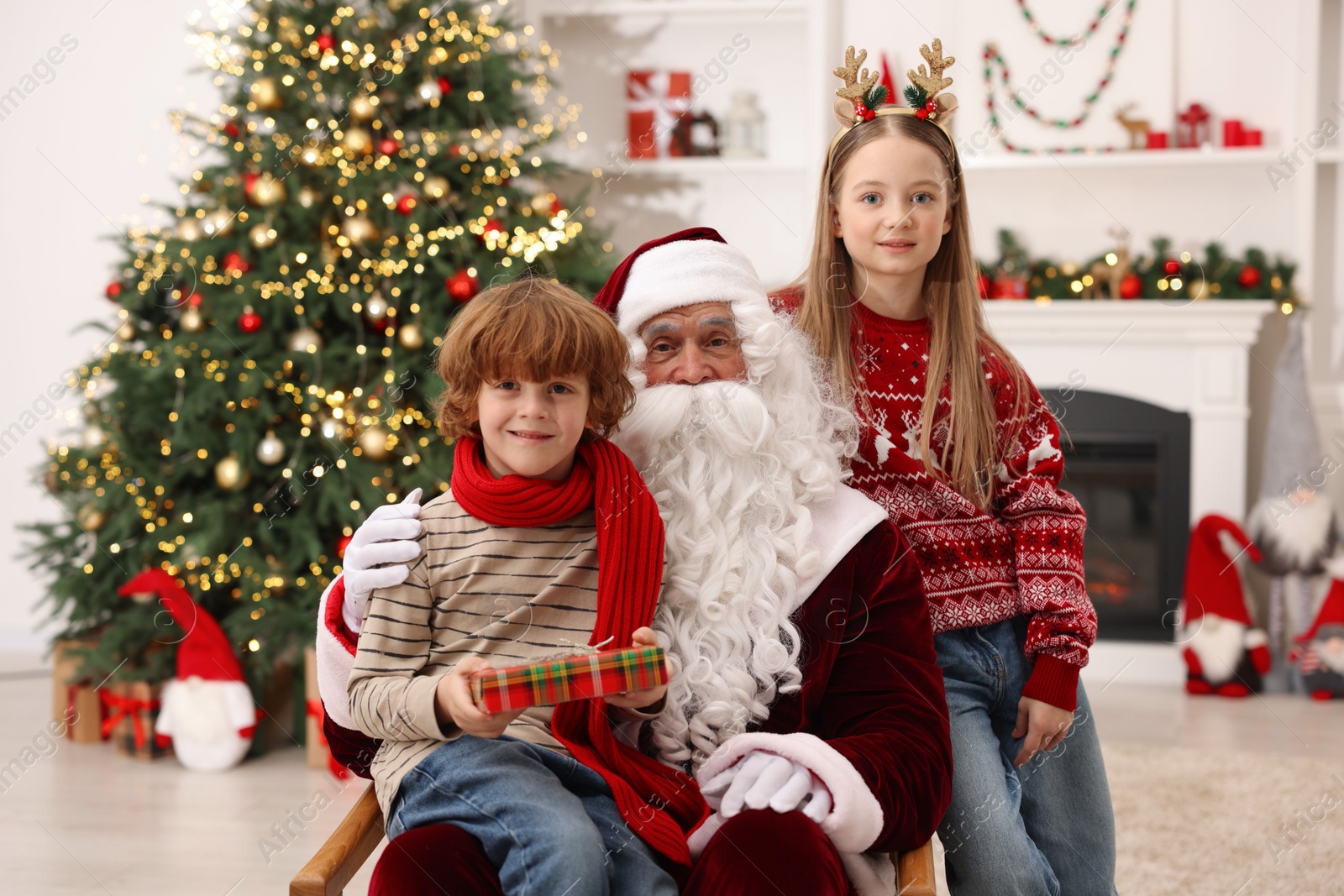 Photo of Christmas celebration. Santa Claus and kids with gift box at home