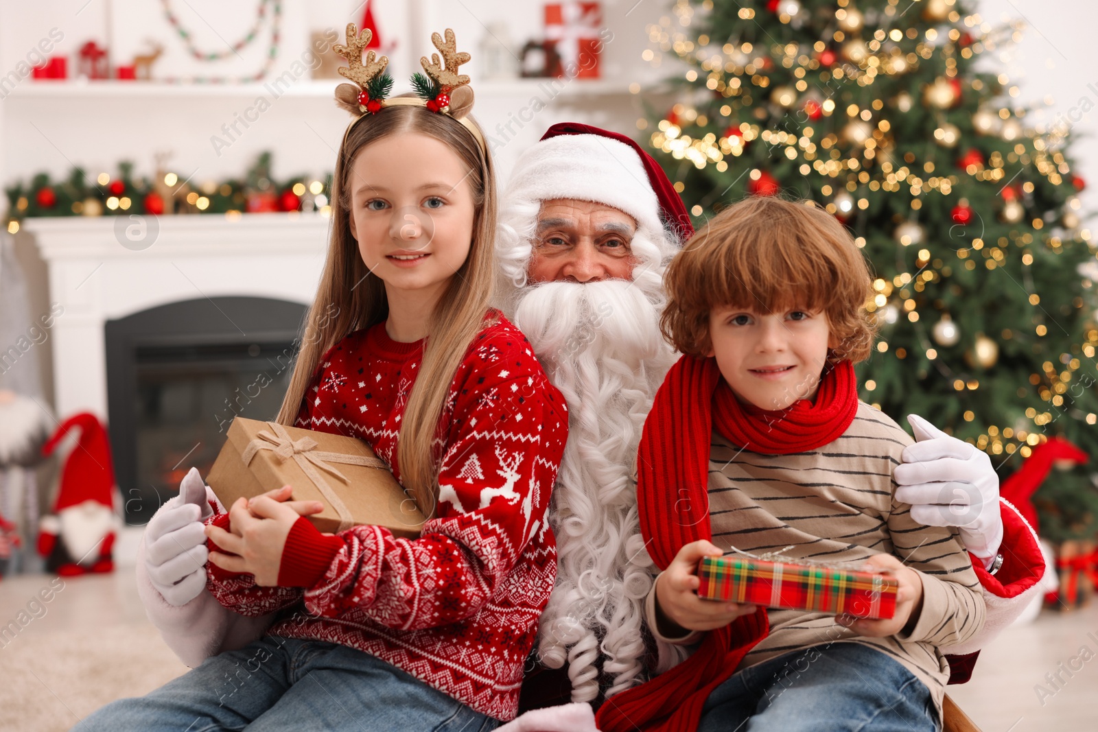 Photo of Christmas celebration. Santa Claus and kids with gift boxes at home