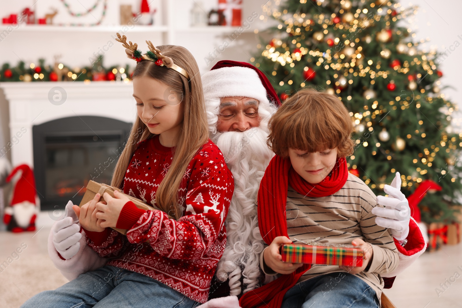 Photo of Christmas celebration. Santa Claus and kids with gift boxes at home