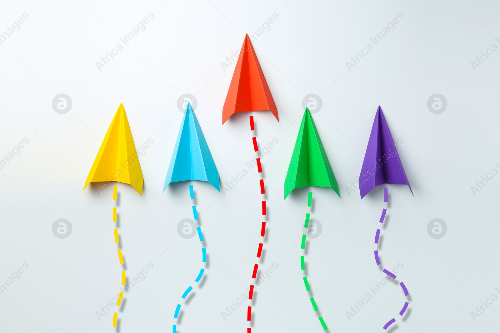 Image of Colorful paper planes with flight paths on white background. Dashed lines for trajectory