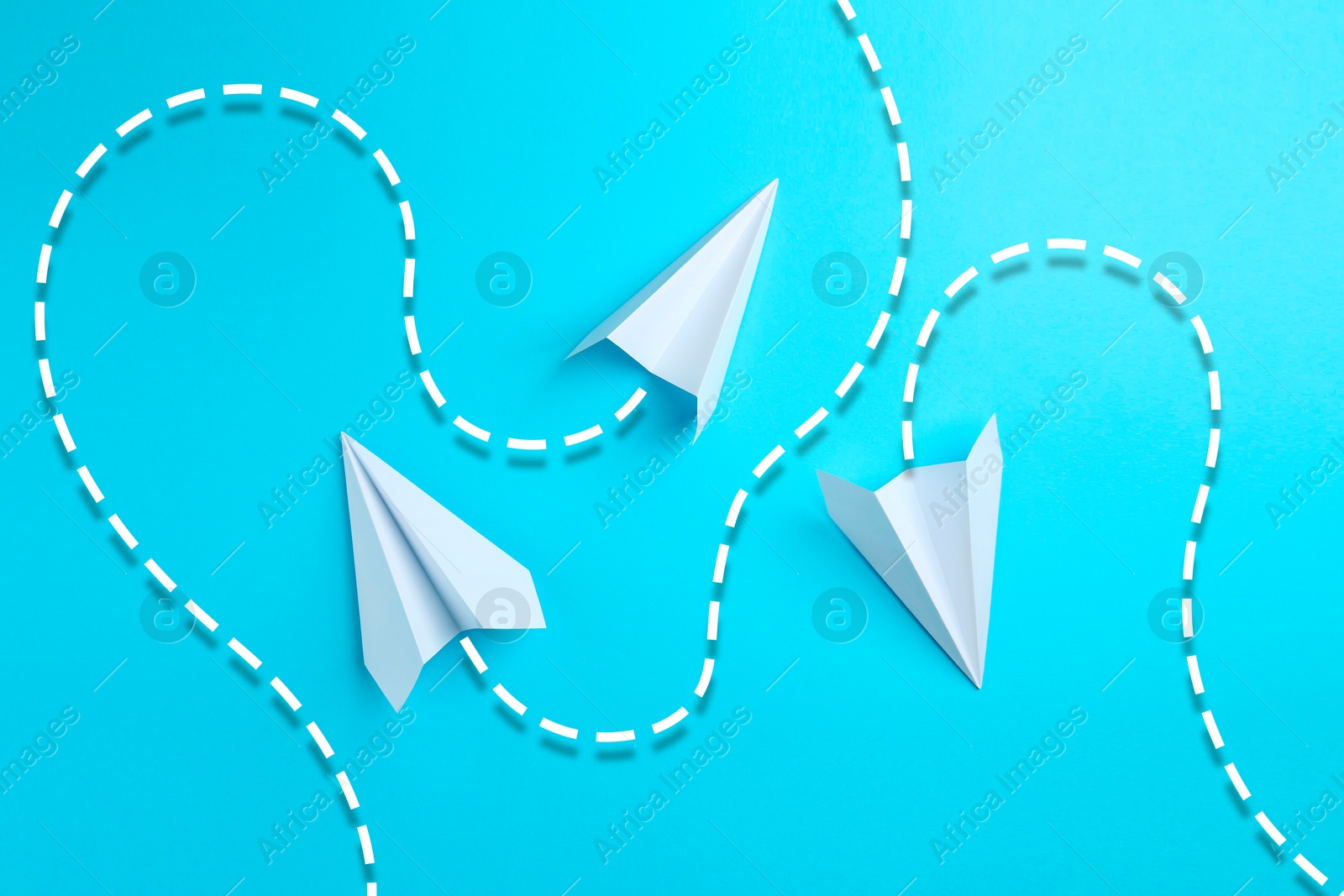 Image of White paper planes with flight paths on light blue background. Dashed lines for trajectory