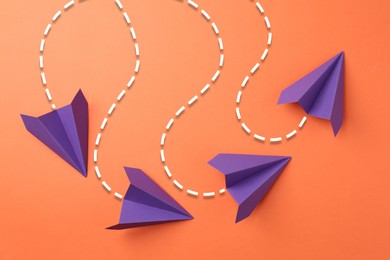 Image of Purple paper planes with flight paths on orange background. Dashed lines for trajectory