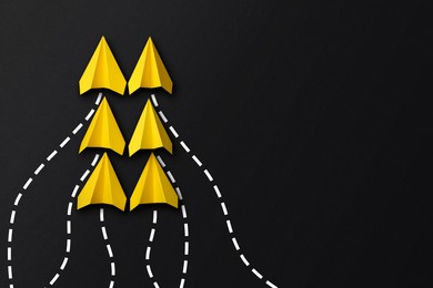 Image of Yellow paper planes with flight paths on black background. Dashed lines for trajectory