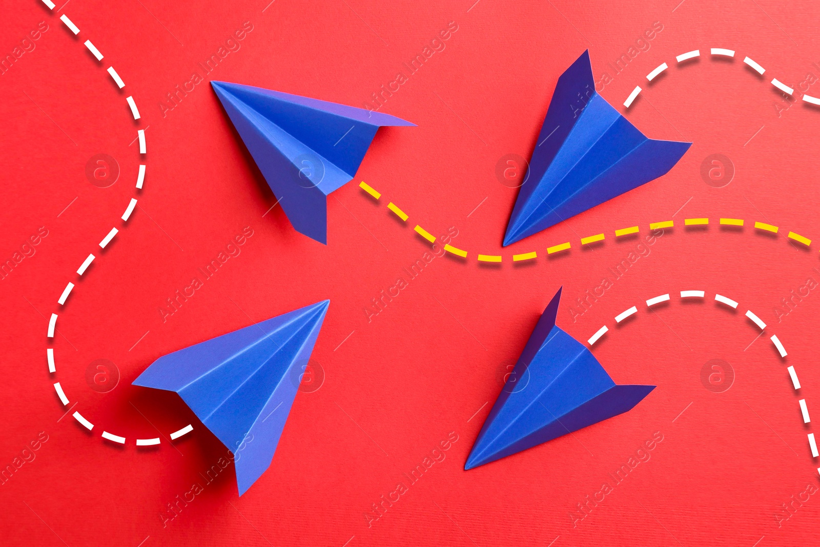 Image of Blue paper planes with flight paths on red background. Dashed lines for trajectory