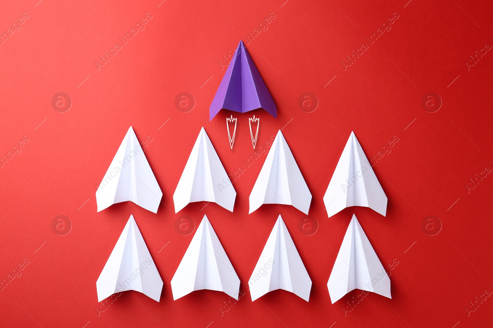 Image of Purple paper plane bursting forward among white ones on red background