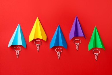 Image of Colorful paper planes rushing forward on red background