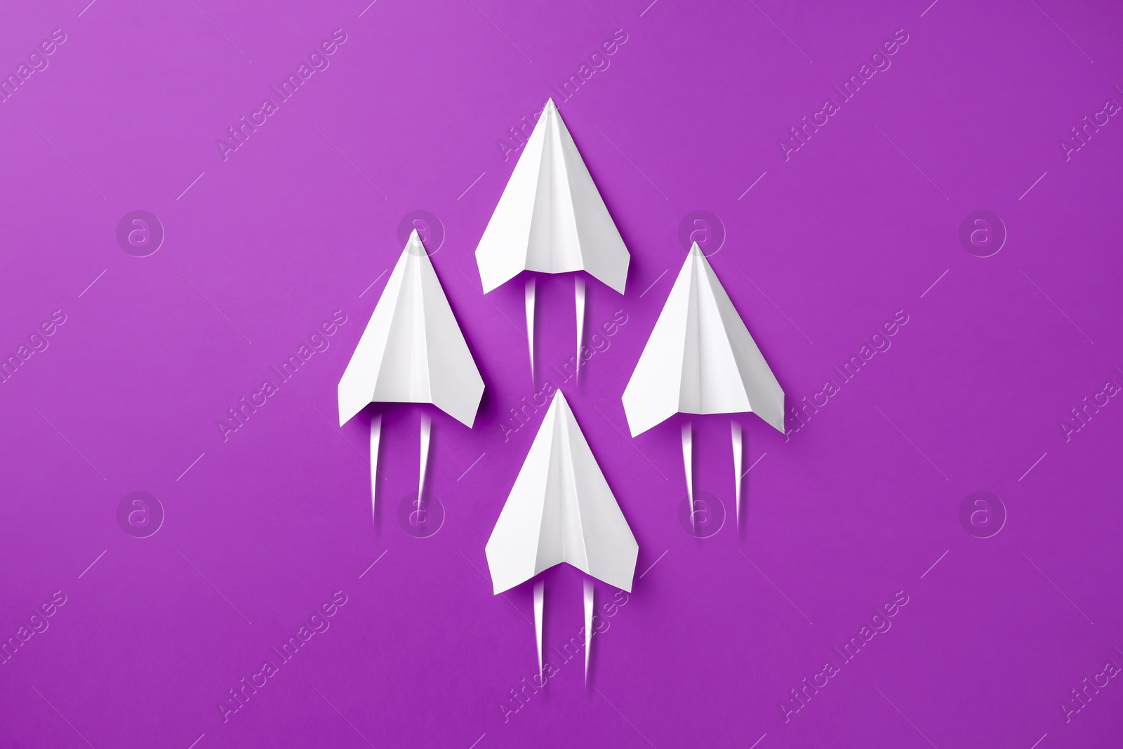 Image of White paper planes rushing forward on purple background