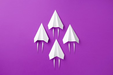 Image of White paper planes rushing forward on purple background