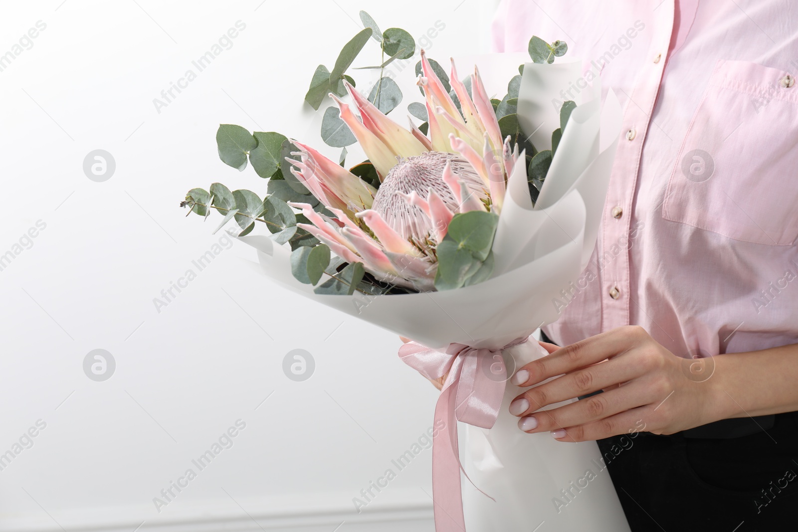 Photo of Woman with beautiful bouquet against light wall, closeup