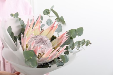 Photo of Woman with beautiful bouquet against light wall, closeup