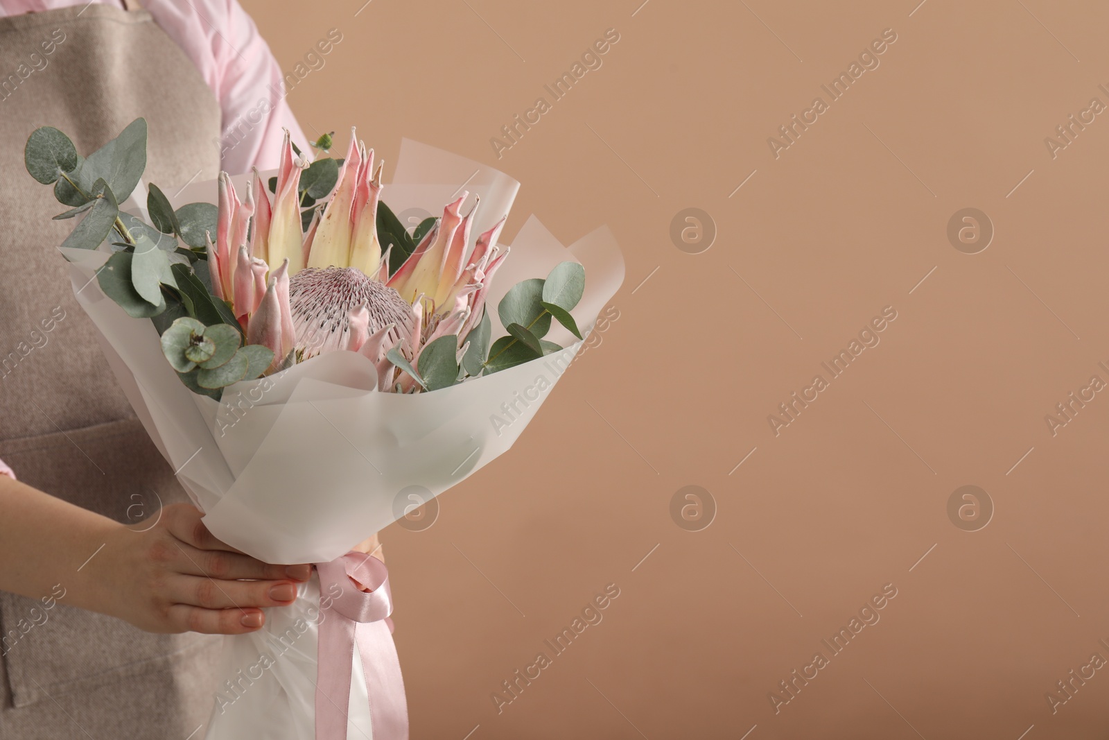 Photo of Florist with beautiful bouquet on brown background, closeup. Space for text