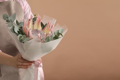 Photo of Florist with beautiful bouquet on brown background, closeup. Space for text