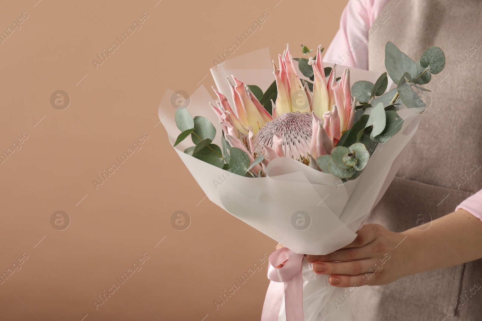 Photo of Florist with beautiful bouquet on brown background, closeup. Space for text