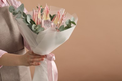 Photo of Florist with beautiful bouquet on brown background, closeup. Space for text