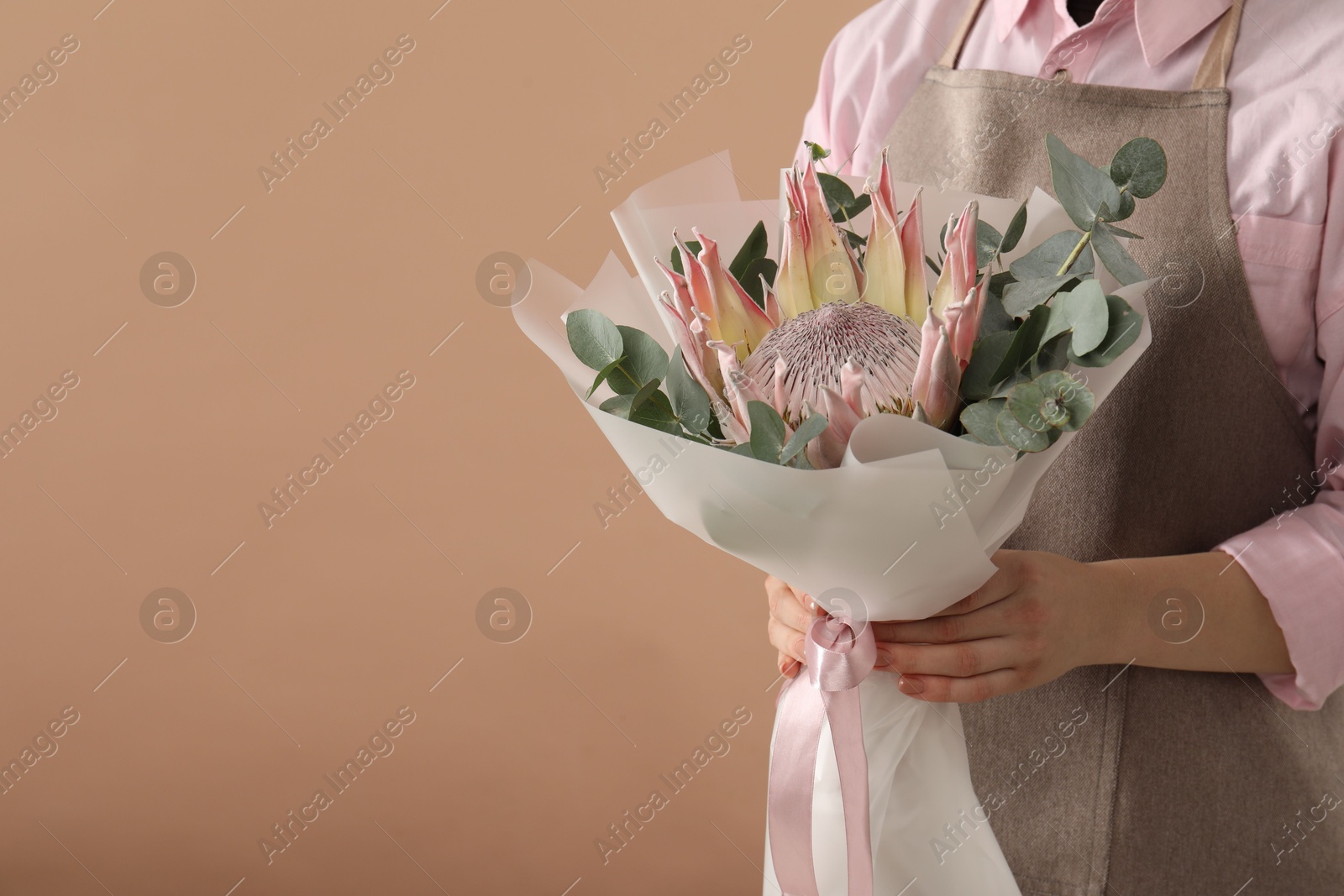 Photo of Florist with beautiful bouquet on brown background, closeup. Space for text