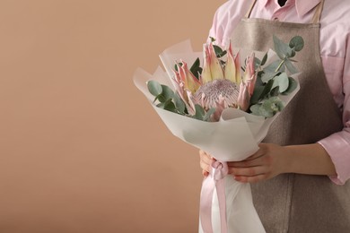 Photo of Florist with beautiful bouquet on brown background, closeup. Space for text