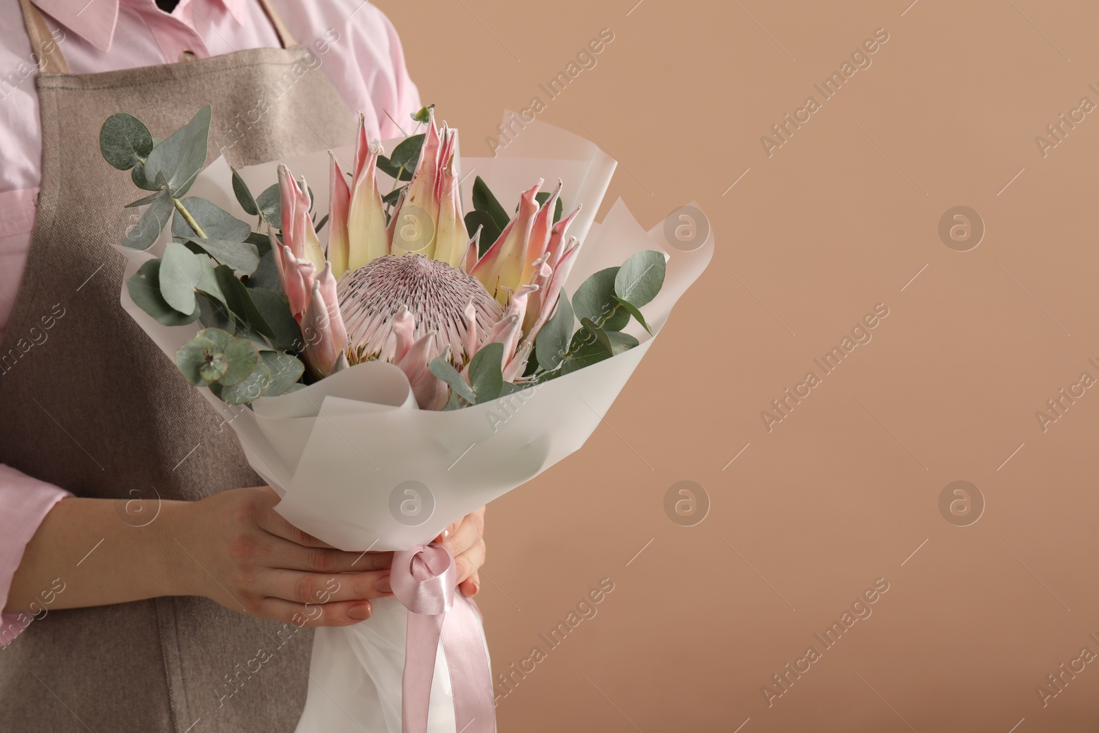 Photo of Florist with beautiful bouquet on brown background, closeup. Space for text