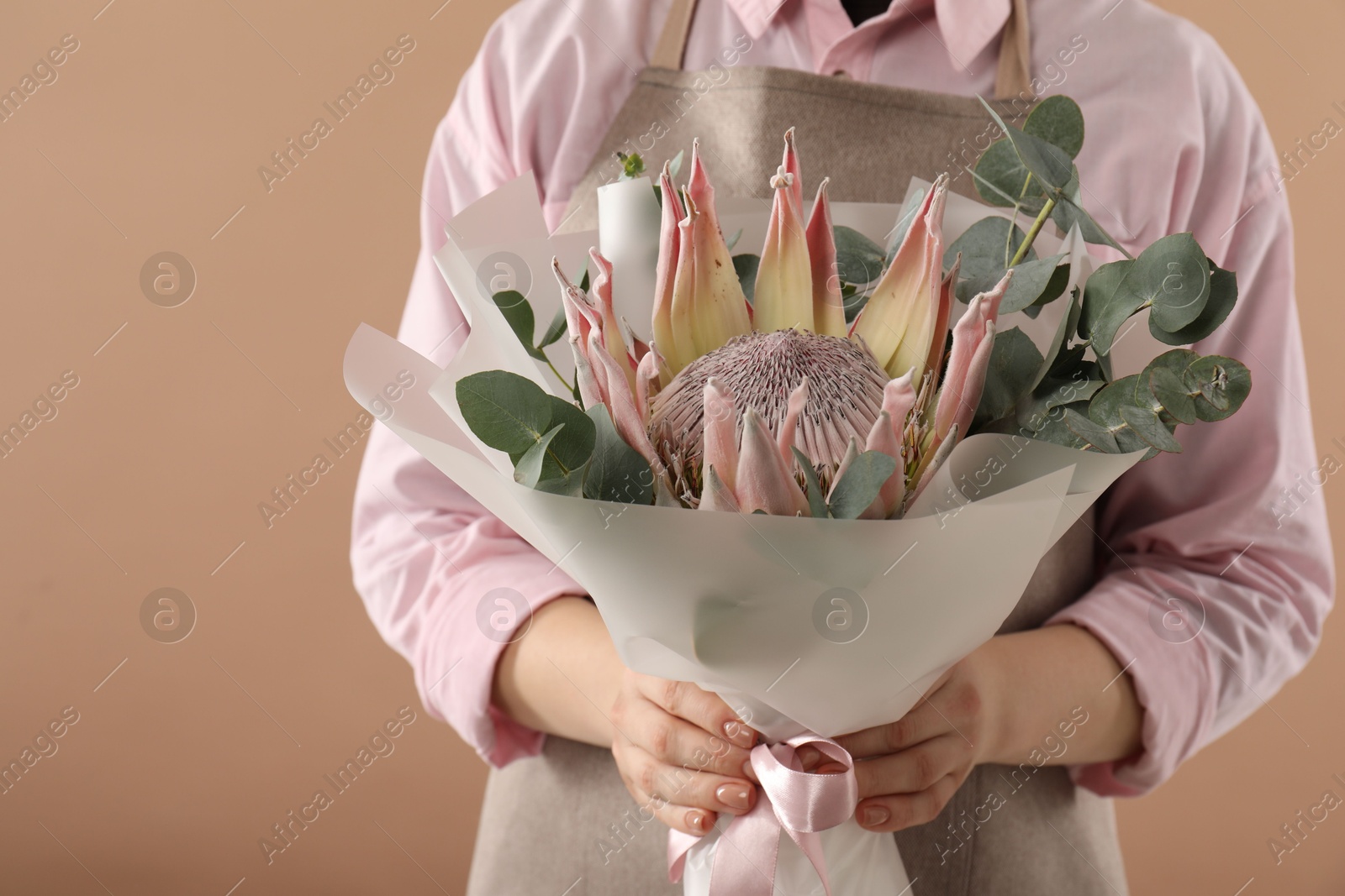 Photo of Florist with beautiful bouquet on brown background, closeup