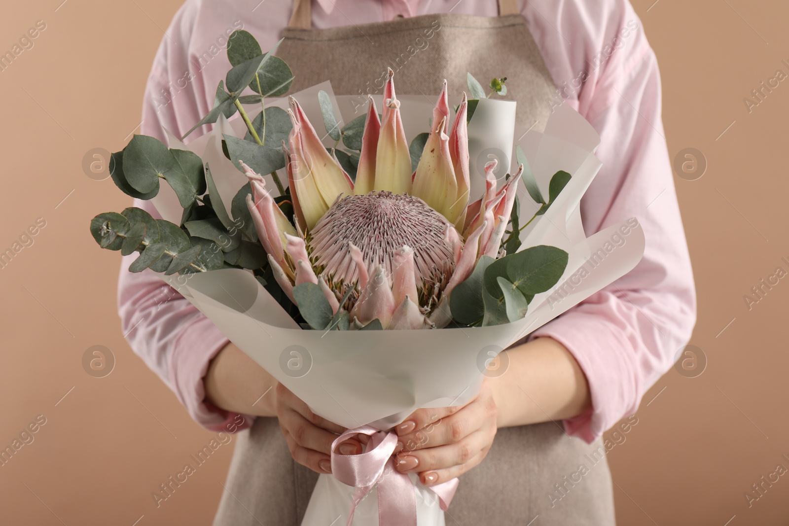 Photo of Florist with beautiful bouquet on brown background, closeup