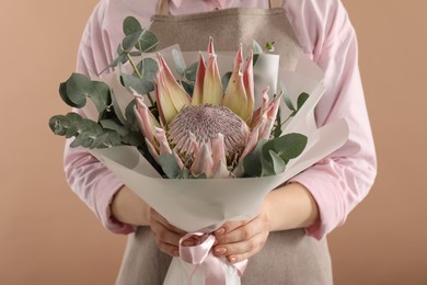 Photo of Florist with beautiful bouquet on brown background, closeup