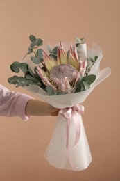 Photo of Woman with beautiful bouquet on brown background, closeup