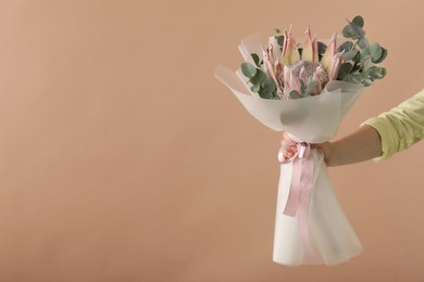 Photo of Woman with beautiful bouquet on brown background, closeup. Space for text