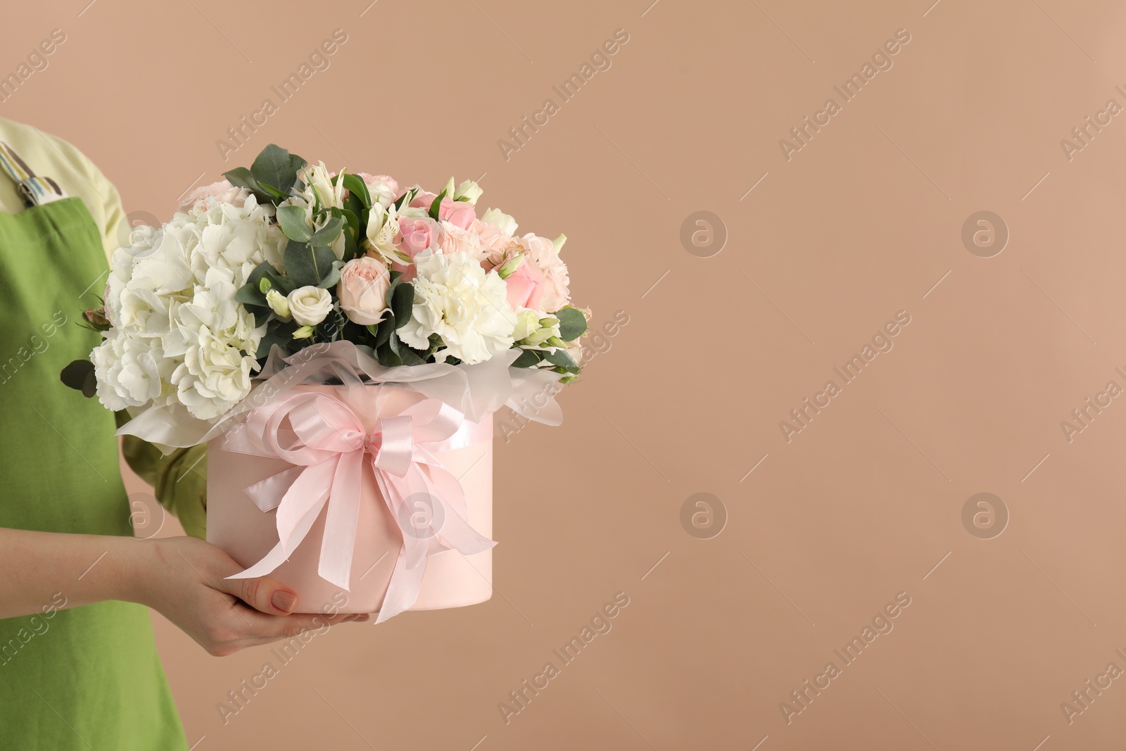 Photo of Florist with beautiful bouquet in box on brown background, closeup. Space for text