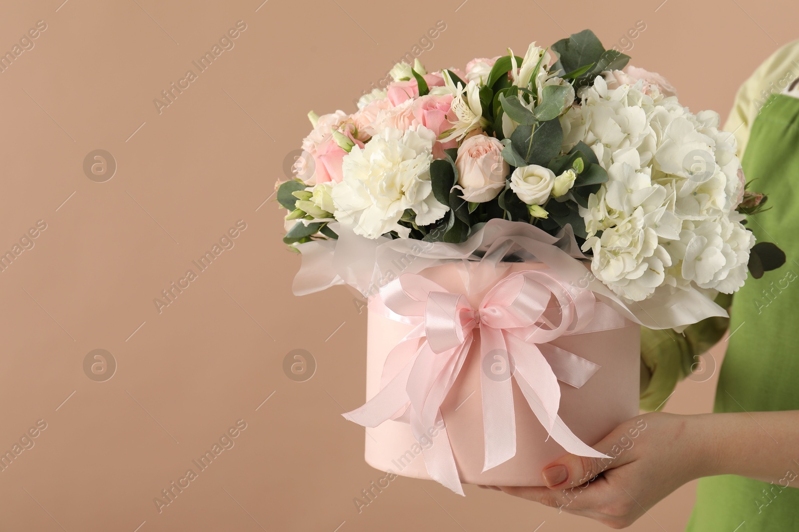 Photo of Florist with beautiful bouquet in box on brown background, closeup. Space for text