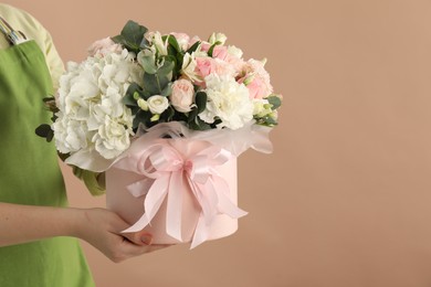 Photo of Florist with beautiful bouquet in box on brown background, closeup. Space for text