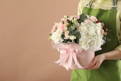 Photo of Florist with beautiful bouquet in box on brown background, closeup. Space for text