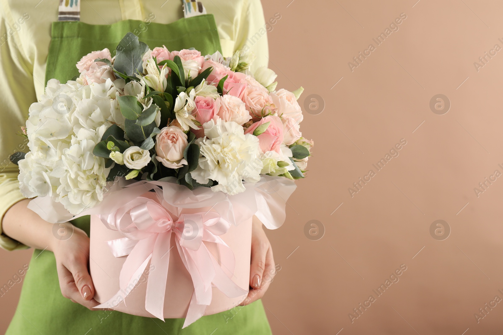 Photo of Florist with beautiful bouquet in box on brown background, closeup. Space for text