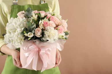 Photo of Florist with beautiful bouquet in box on brown background, closeup. Space for text