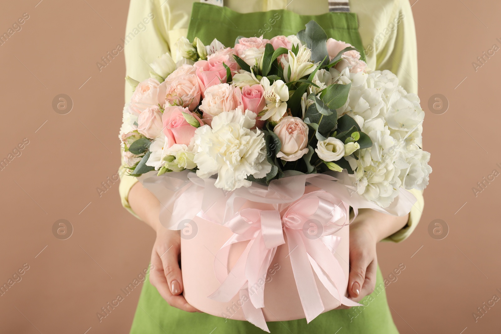 Photo of Florist with beautiful bouquet in box on brown background, closeup