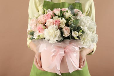 Photo of Florist with beautiful bouquet in box on brown background, closeup