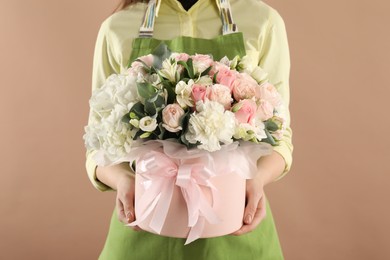 Photo of Florist with beautiful bouquet in box on brown background, closeup